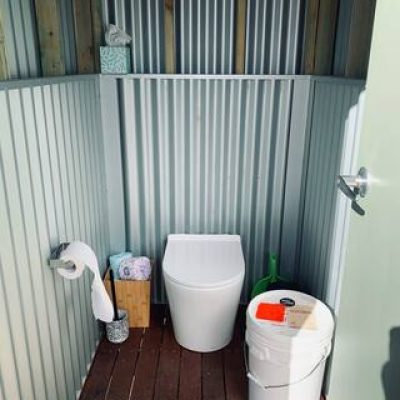 Composting toilet with toilet paper, brush, wipes, tissues and sawdust provided.